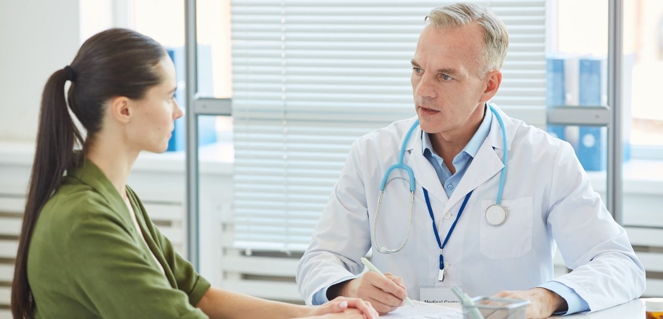 Mature Doctor Talking to Woman in Clinic