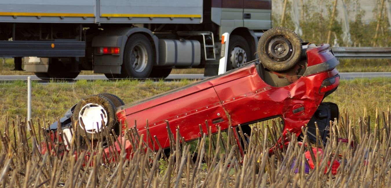 red car in a field after accident with a truck